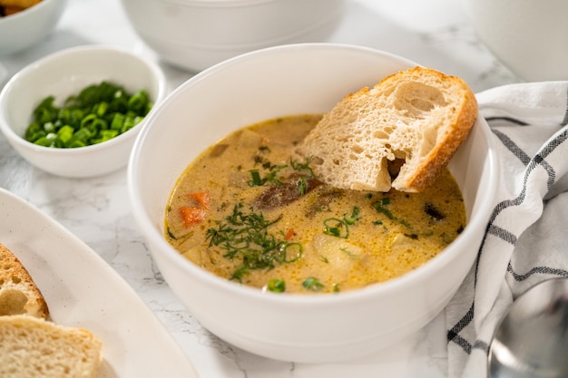 Servir sopa cremosa de champiñones silvestres hecha de champiñones silvestres deshidratados en tazones blancos con pan de masa fermentada