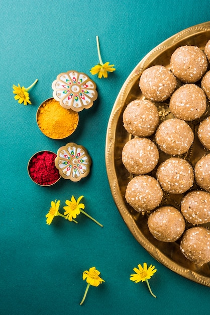 Foto sésamo ou ril gul ou tilgul laddu com haldi kumkum com flores para o festival makar sankranti, foco seletivo