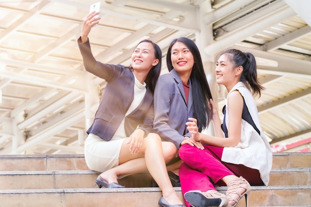 Sesión de empresaria y uso de teléfono inteligente para tomar selfie con colega juntos