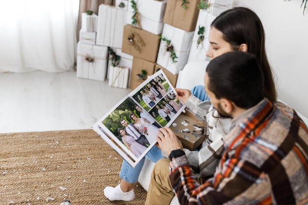 Sesión de fotos en el estudio de una pareja joven Un chico con una chica está celebrando la historia de amor de Navidad Año Nuevo Una pareja mira las fotos de su boda