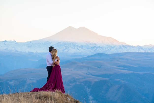 Sesión de fotos en las montañas. chica en un vestido contra las montañas. al atardecer