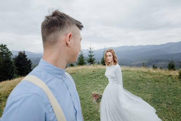 Sesión de fotos de la novia y el novio en las montañas. Foto de boda de estilo boho.