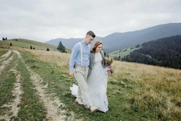 Sesión de fotos de la novia y el novio en las montañas. Foto de boda de estilo boho.