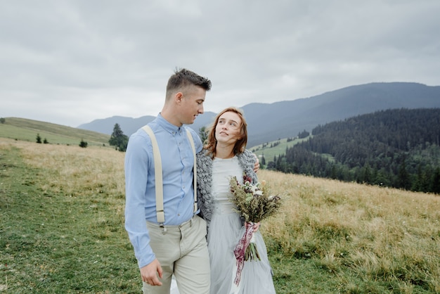 Sesión de fotos de la novia y el novio en las montañas. Foto de boda de estilo boho.