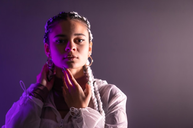 Sesión urbana. Retrato de una joven mujer caucásica con largas trenzas blancas sobre un fondo liso