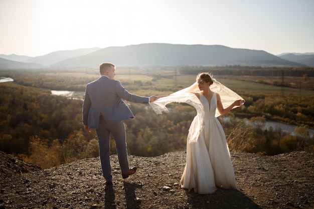 Sessão de fotos de casamento da noiva e do noivo nas montanhas. Sessão de fotos ao pôr do sol.