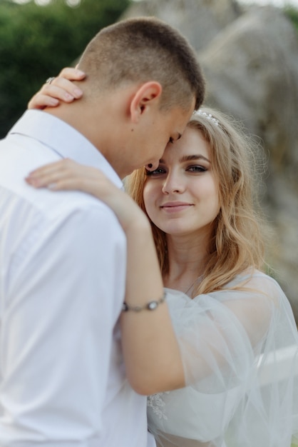 Sessão de fotos de um casal apaixonado nas montanhas. A garota está vestida como uma noiva em um vestido de noiva.