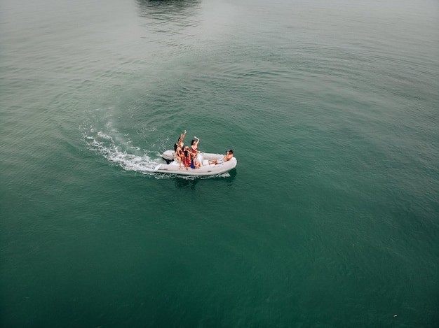 Sessão de fotos turísticas em um navio branco. Mulheres muito bonitas em trajes de banho fofos estão posando alegremente para um cara de boné preto que está tirando fotos delas. O conceito de foto fria.