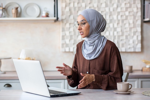 Sessão de psicoterapia online, uma jovem psicóloga muçulmana em um hijab senta-se em casa na frente de