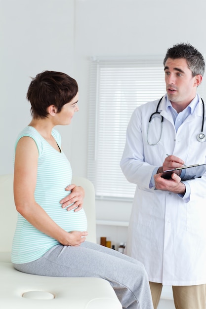 Foto sessão, mulher grávida, conversando com seu médico