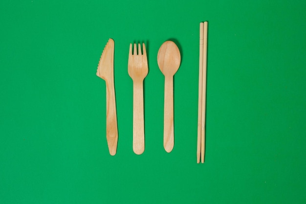 Set aus Holzgabel, Löffel, Messer, Bambuszahnbürste, isoliert auf grünem Hintergrund