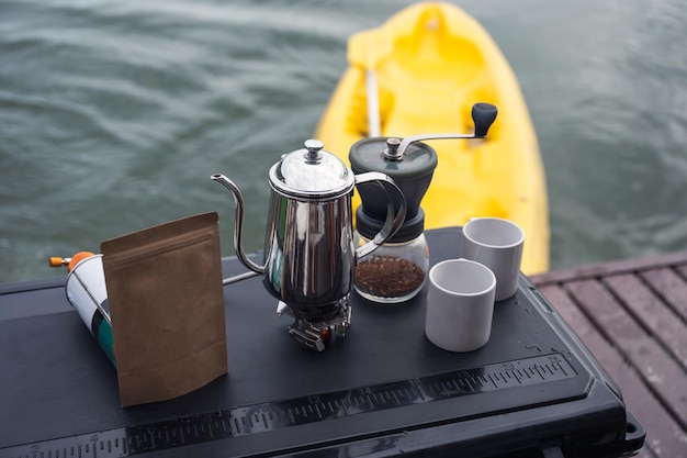 Set aus manueller Kaffeemühle mit Becher auf Gasherd und weißer Tasse