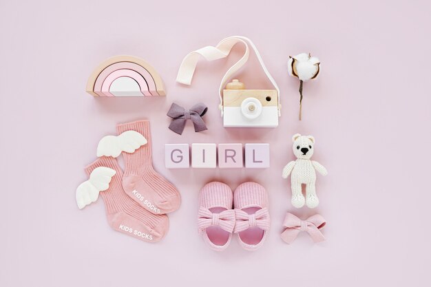 Set Babysachen und Zubehör für Mädchen auf pastellfarbenem Hintergrund. Rosa Socken, Schuhe und Spielzeug. Baby-Dusche-Konzept. Mode Neugeborenes. Flache Lage, Ansicht von oben