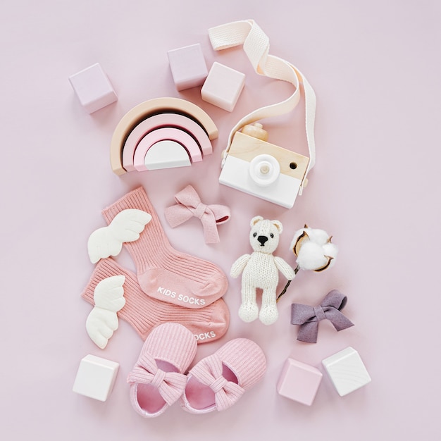 Set Babysachen und Zubehör für Mädchen auf pastellfarbenem Hintergrund. Rosa Socken, Schuhe und Spielzeug. Baby-Dusche-Konzept. Mode Neugeborenes. Flache Lage, Ansicht von oben