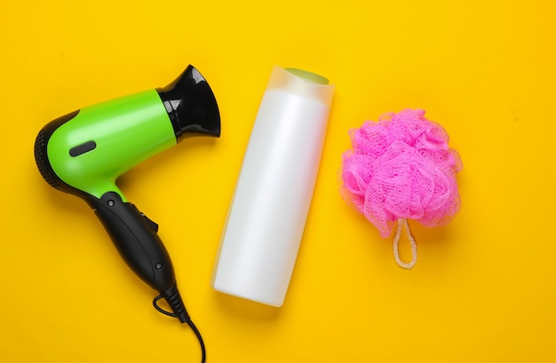 Set de baño, productos y dispositivos para el cuidado del cabello. Secador de pelo con botella de champú, botella de baño en amarillo