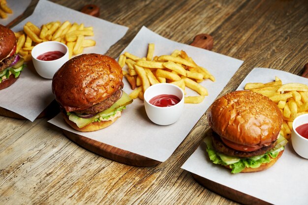 Set Burger mit Pommes Frites und Ketchup-Sauce. Große Hamburger und Pommes Frites auf hölzernem Tischhintergrund. Fast-Food-Set Hintergrund. Restaurant Burger Menü