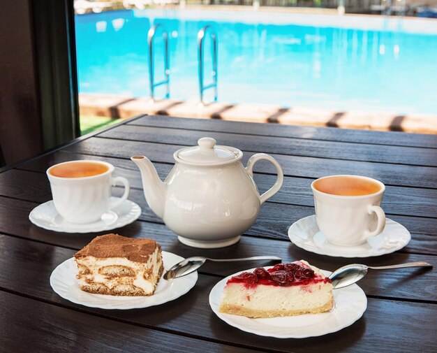 Foto set de chá da tarde com chá quente e bolos saborosos na mesa e na piscina conceito de resort de hotel ou descanso