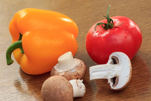 Set guter Naturprodukte mit frischem gelbem Pfeffer, roten Tomaten und Pilzen auf dem Küchentisch