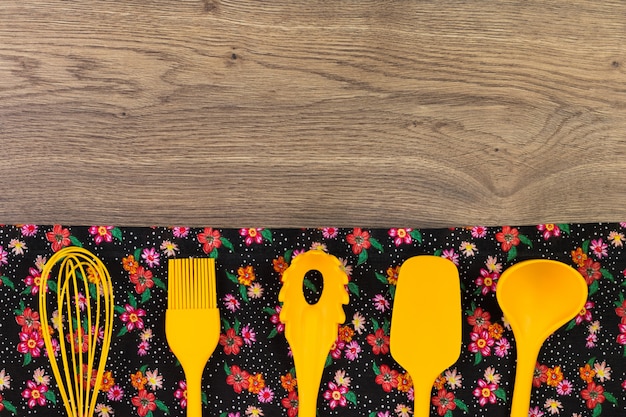 Set Küchenutensilien. Blumenstoffserviette auf Holztisch.