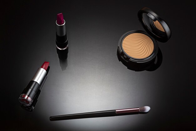 Set de maquillaje cosmético visto desde arriba en negro con iluminación puntual.