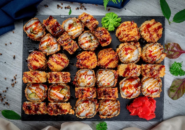 Set mit gebratenen und gebackenen Rollen Sushi auf einem Steinbrett auf einem Leuchttisch