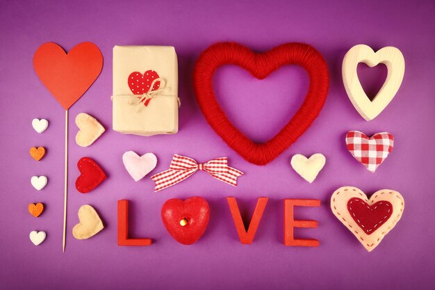 Set de regalo para el Día de San Valentín con caja de palabras de amor y velas sobre fondo morado