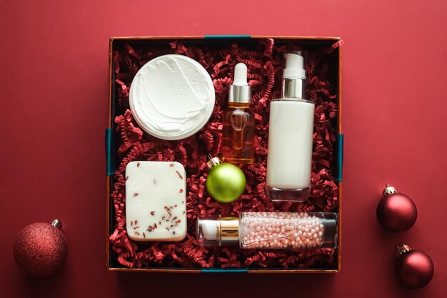 Set de regalo de navidad paquete de suscripción de caja de belleza de vacaciones de navidad y productos de lujo para el cuidado de la piel plano cosmético plano sobre fondo de coral cosméticos como regalo de vacaciones o entrega de compras