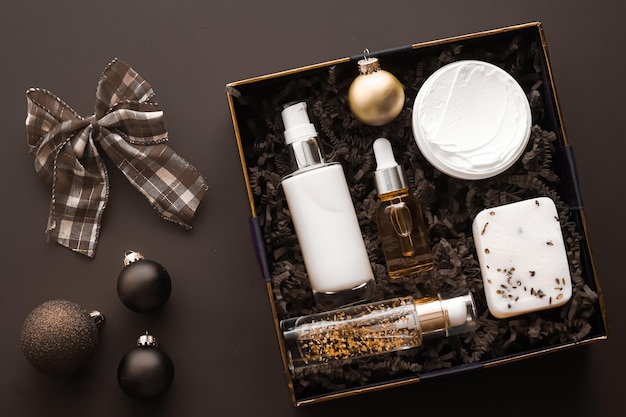 Set de regalo de navidad paquete de suscripción de caja de belleza de vacaciones de navidad y productos de lujo para el cuidado de la piel plano cosmético plano sobre fondo oscuro cosméticos como regalo de vacaciones o entrega de compras