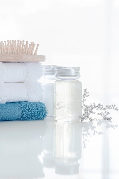 Set de spa con pila de toallas limpias, botella de aceite, peine de madera y flores.