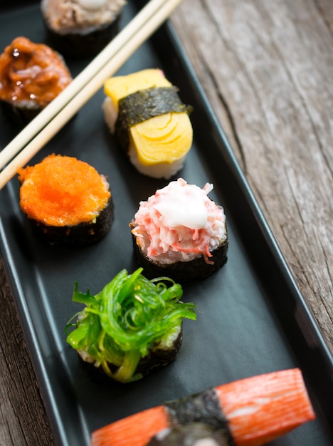 Set de sushi y rollos de sushi servidos en mesa de madera.