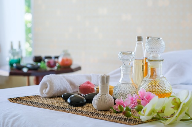 Set de tratamiento de spa y aceite de masaje aromático en cama. Ambiente tailandés para aromaterapia y masajes con flores en la cama, relajación y cuidado saludable.