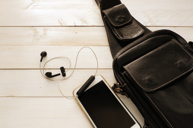 Foto set de viaje con bolso negro de cuero y teléfono inteligente