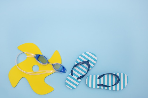 Set von Artikeln für Strandspielzeug Schwimmbrillen Kinder Flip Flops auf blauem Hintergrund mit Kopierraum