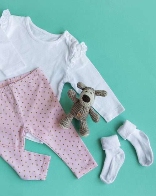 Foto set von baby-bodysuits, hosen, socken und gestricktem spielzeug