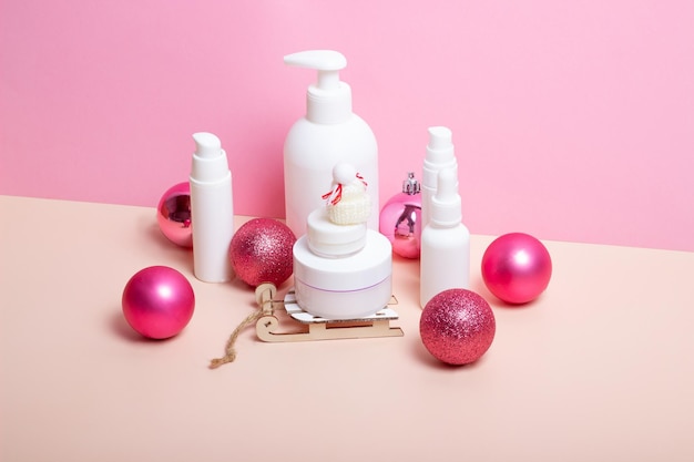 Set von Hautpflegekosmetik auf Weihnachtsschlitten und Christbaumschmuck Feuchtigkeitsspendende Gesichtscreme mit weihnachtlichen Accessoires Winter-Hautpflegekonzept