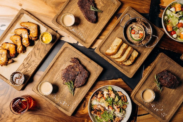 Set von leckeren Gerichten auf dem Tisch Restaurant mit Rindfleisch Steak Salat und Barbecue Hühnerflügel Flachlag Essen Menü Konzept