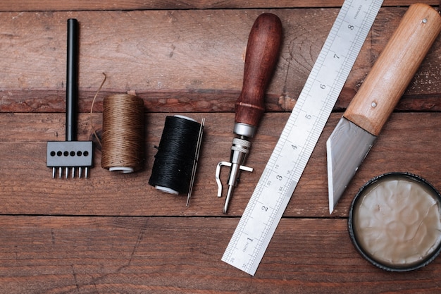 Set von lederhandwerkswerkzeugen. schuhmacherwerkzeuge auf holztisch.