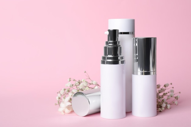 Set von luxuriösen Kosmetikprodukten und Blumen auf rosa Hintergrund Platz für Text