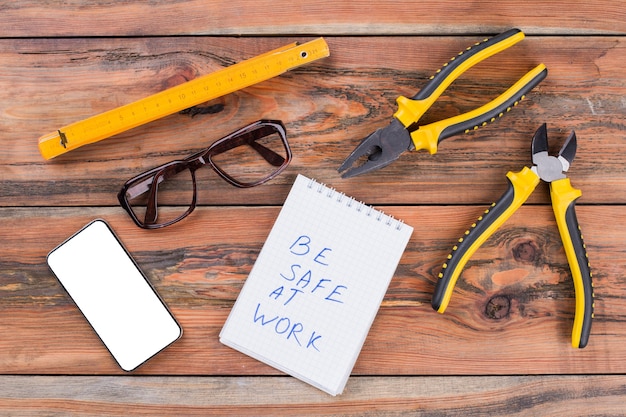 Set von Tischler-Arbeitswerkzeugen Smartphone-Brille auf strukturiertem Holzschreibtisch