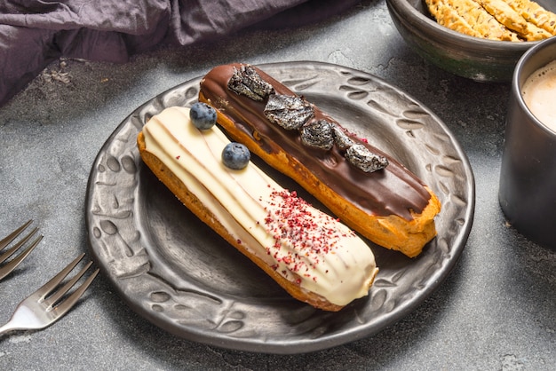 Set von verschiedenen Eclair-Kuchen auf dunklen Hintergrund