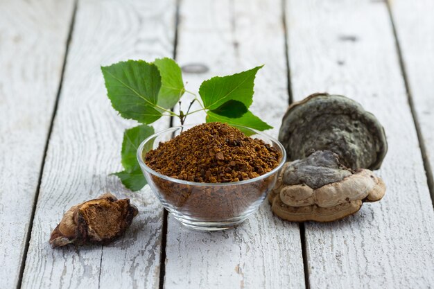 Seta de abedul chaga con hojas de abedul sobre una mesa de luz. Setas de abedul en gránulos. fitoterapia. Superalimento orgánico. estilo rústico