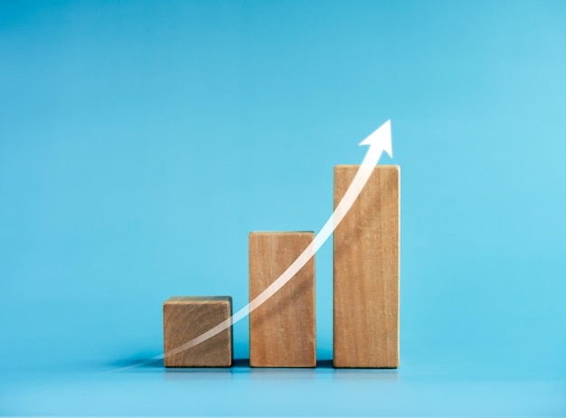 Seta ascendente brilhante no gráfico de barras de blocos de cubo de madeira passos no fundo azul lucro benefício renda processo de crescimento de negócios tecnologia tendência de melhoria econômica conceitos estilo mínimo