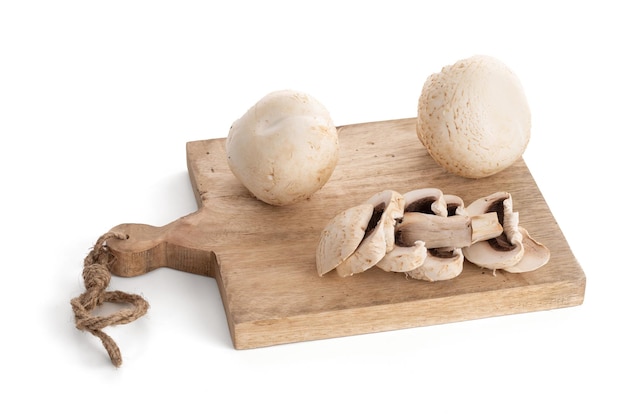 Seta de botón blanco Agaricus Bisporus sobre una tabla para cortar sobre fondo blanco