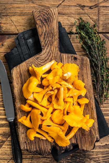 Setas de chanterelles salvajes crudas sin cocer en una tabla de cortar Fondo de madera Vista superior