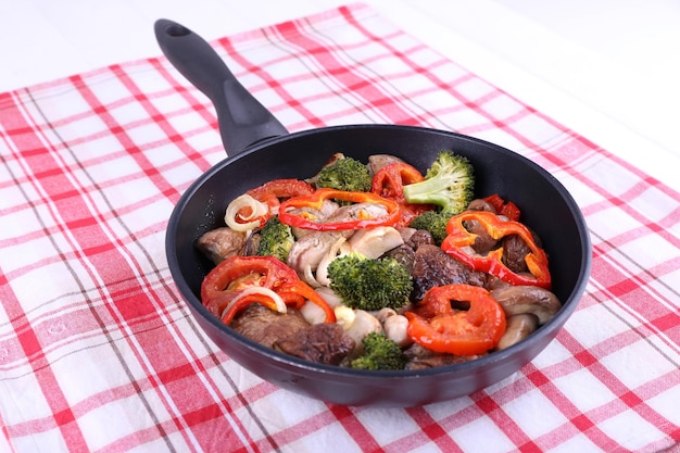 Setas estofadas con verduras y especias en una sartén sobre un mantel