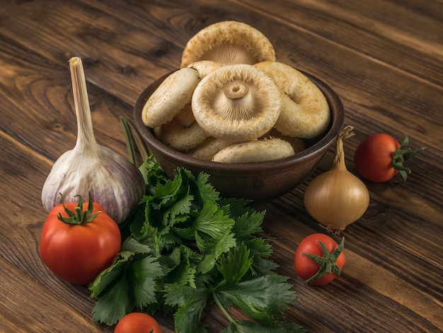 Setas frescas del bosque tomates ajo y hierbas en una mesa de madera