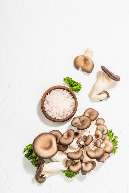 Setas de ostra frescas con perejil y sal marina Ingrediente saludable para cocinar comida vegana Fondo blanco luz dura sombra oscura plano vista superior