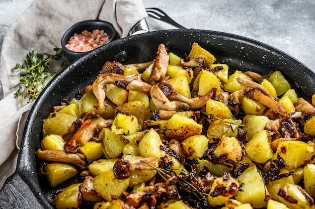 Setas de ostra fritas con patatas en una sartén. fondo gris vista superior