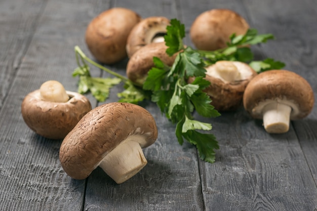 Las setas reales están esparcidas sobre una mesa de madera negra con hojas de perejil. Comida vegetariana. Hongos cultivados artificialmente.