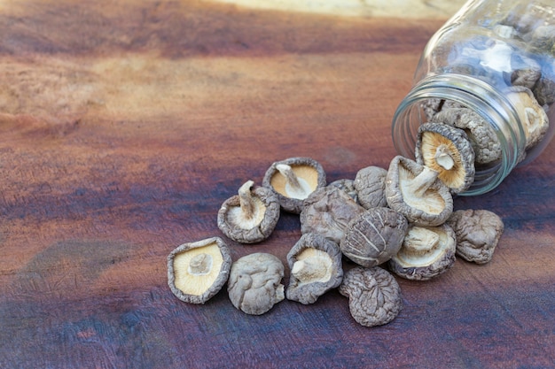 Setas de shiitake secadas en un tarro de cristal y setas de shiitake secadas en una tabla de madera.